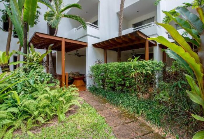 Avani Pattaya Resort garden path. Gay-friendly hotel with lush greenery, wooden pavilions, and tropical plants. Ideal for gay men travelers.