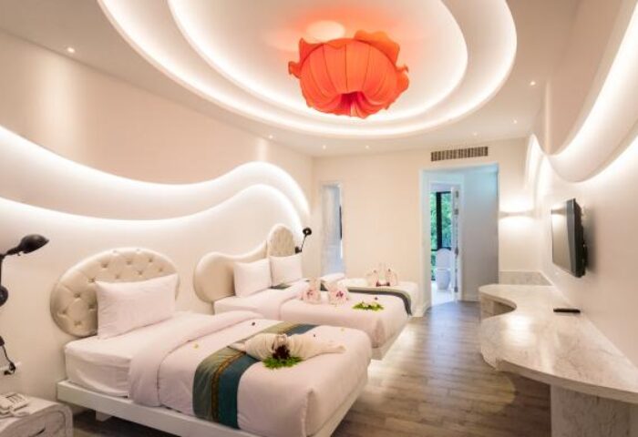 Avatara Resort gay-friendly hotel room. Two beds with decorative towels, flower lamp, and modern design. Gay travel lodging.