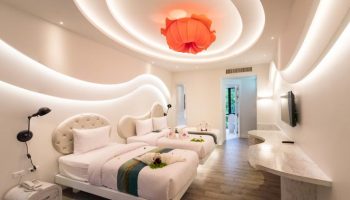 Avatara Resort gay-friendly hotel room. Two beds with decorative towels, flower lamp, and modern design. Gay travel lodging.