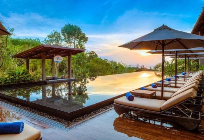 Avista Hideaway Phuket Patong MGallery by Sofitel's infinity pool at sunset. Gay-friendly hotel with luxury loungers and stunning views.