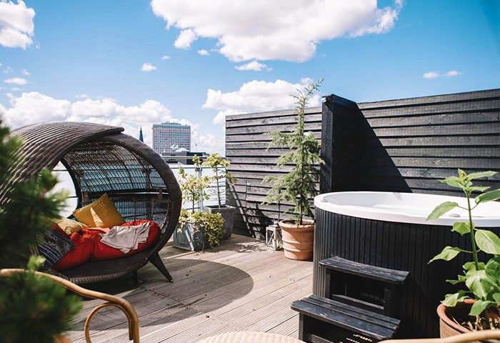 Rooftop terrace at Axel Guldsmeden, a gay-friendly hotel. Features a hot tub, lounge chair, plants, & city views. Perfect for LGBT travel.