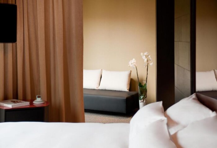 Axel Hotel Berlin-Adults Only detail. Gay-friendly hotel room with bed, couch, and orchid. Modern design, inviting ambiance. Perfect for gay travel.