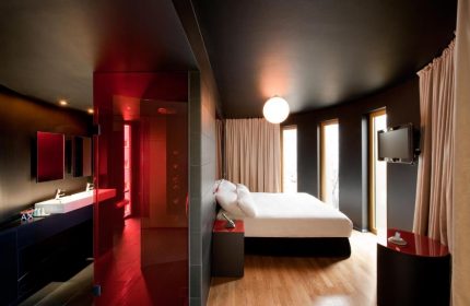 Axel Hotel Berlin Adults Only room. Modern design, red glass bathroom, sleek furniture, and a comfortable bed. Gay-friendly hotel.