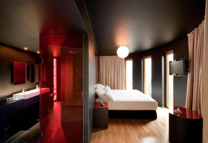 Axel Hotel Berlin Adults Only room. Modern design, red glass bathroom, sleek furniture, and a comfortable bed. Gay-friendly hotel.