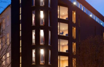 Axel Hotel Berlin-Adults Only. Gay-friendly hotel with modern architecture, illuminated windows, and the Axel Hotel sign at dusk.