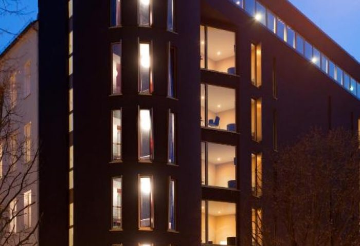 Axel Hotel Berlin-Adults Only. Gay-friendly hotel with modern architecture, illuminated windows, and the Axel Hotel sign at dusk.