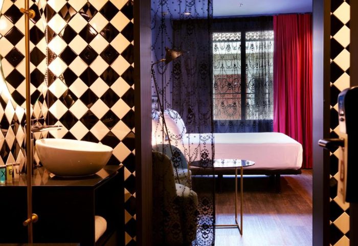 Axel Hotel Madrid adults-only gay hotel room. Modern design with black and white tiles, red curtains and a peek into the bedroom.