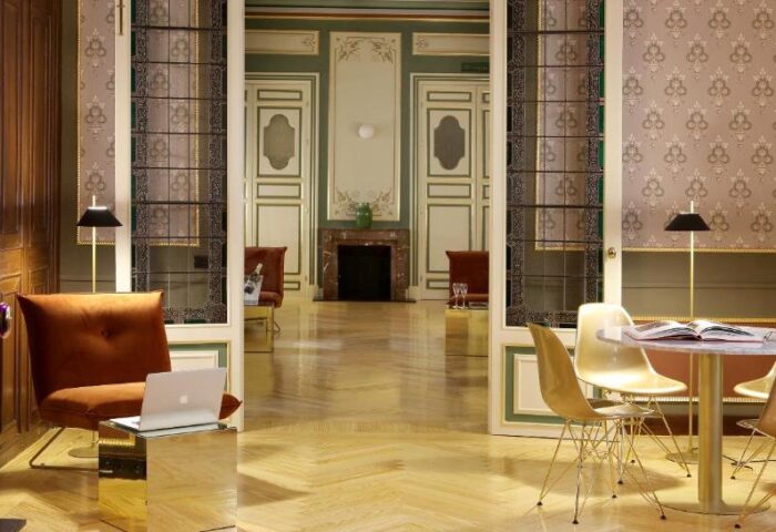 Axel Hotel Madrid Adults Only interior. Lounge area with table, chairs, and laptop. Gay-friendly hotel design, perfect for gay men travel.