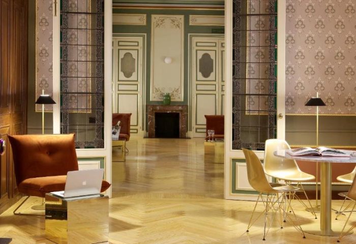 Axel Hotel Madrid Adults Only interior. Lounge area with table, chairs, and laptop. Gay-friendly hotel design, perfect for gay men travel.