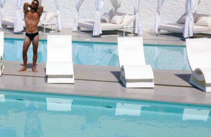 AxelBeach Ibiza Suites: Gay-friendly, adults-only hotel pool scene. Man in swimwear near lounge chairs. Spa and beach club vibe.