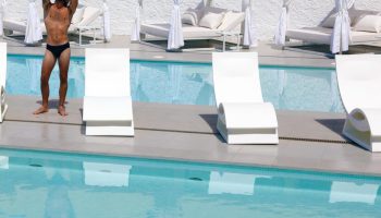 AxelBeach Ibiza Suites: Gay-friendly, adults-only hotel pool scene. Man in swimwear near lounge chairs. Spa and beach club vibe.