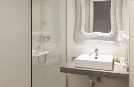 Bathroom at AxelBeach Ibiza Suites, a gay-friendly, adults-only hotel. Features a shower, sink, and unique mirror. Ideal for gay travel.