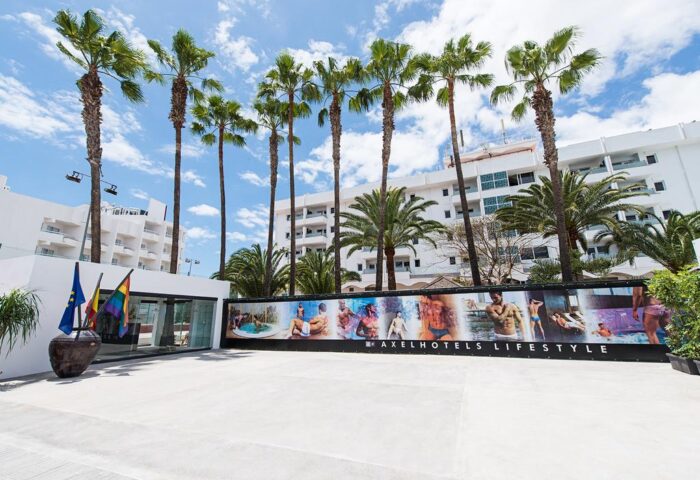 AxelBeach Maspalomas ApartLoungeClub entrance. Gay-friendly, adults-only hotel with palm trees and a banner featuring attractive men.