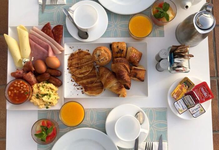 Breakfast at AxelBeach Maspalomas, a gay-friendly, adults-only hotel. Table setting with pastries, eggs, beans, juice, and coffee.