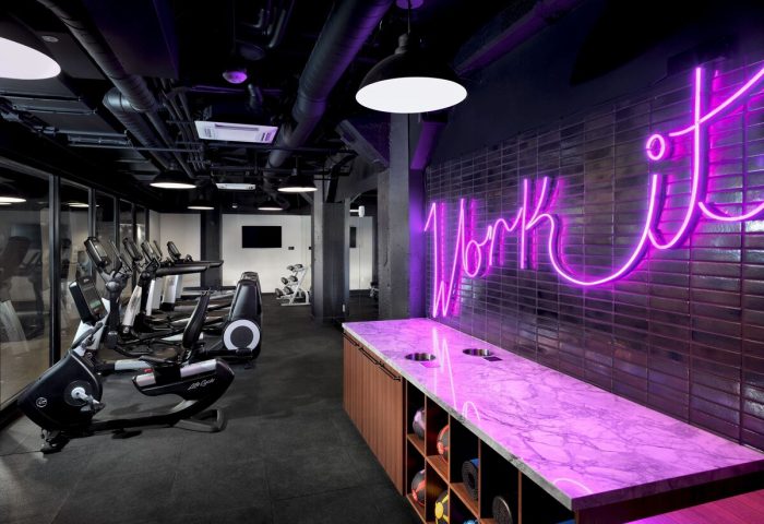 Axiom Hotel's gym. Gay-friendly hotel fitness center with treadmills, weights, and a Work It neon sign. Modern design.