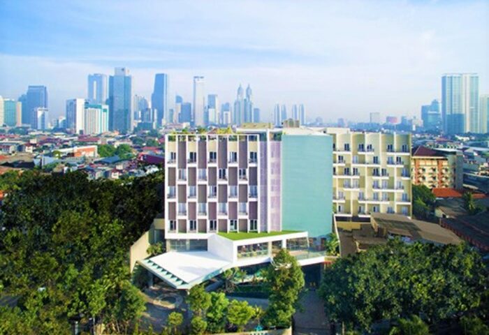 Ayaka Suites, a gay-friendly hotel. Modern building with city skyline backdrop. Ideal for gay travelers seeking comfort and style.