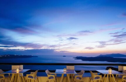 Azzurro Suites, gay-friendly hotel view. Tables overlook the sea at sunset. Gay travel destination in Santorini, Greece.