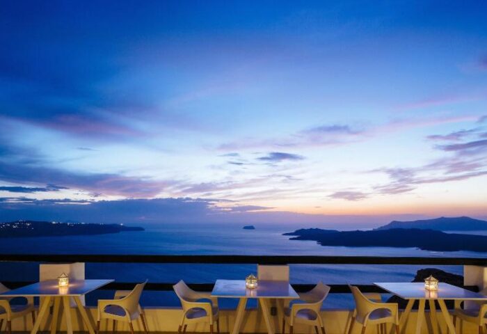 Azzurro Suites, gay-friendly hotel view. Tables overlook the sea at sunset. Gay travel destination in Santorini, Greece.