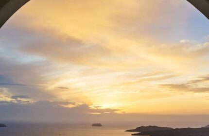 Sunset view from Azzurro Suites, a gay-friendly hotel. Two wine glasses sit by the pool, reflecting the sky. Romantic travel for gay men.