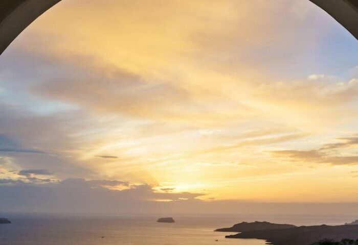 Sunset view from Azzurro Suites, a gay-friendly hotel. Two wine glasses sit by the pool, reflecting the sky. Romantic travel for gay men.