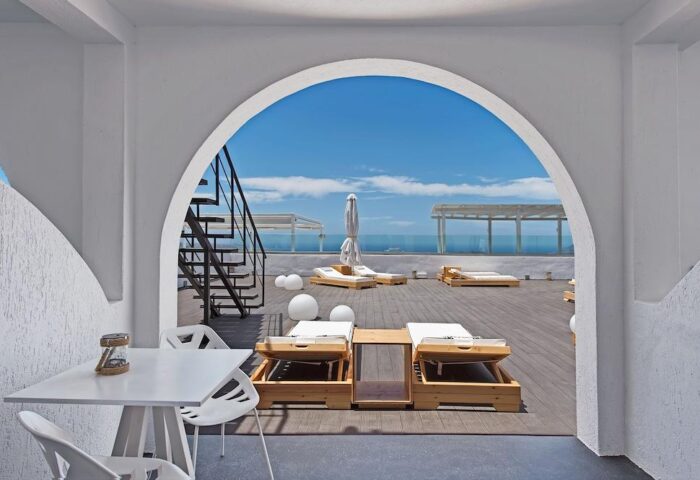 Azzurro Suites gay-friendly hotel rooftop. Lounge chairs, table, and stairs. A perfect spot for gay travelers seeking relaxation. Blue sky view.