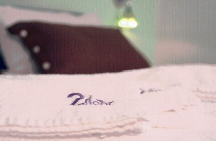 Gay-friendly hotel B&B second floor. Towels with 2floor embroidery, bed, and lamp. Gay travel lodging advice.