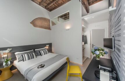 B&B First Floor room: Gay-friendly hotel bedroom with a bed, closet, TV, flowers, and coffee machine. Modern design, comfortable for gay travelers.