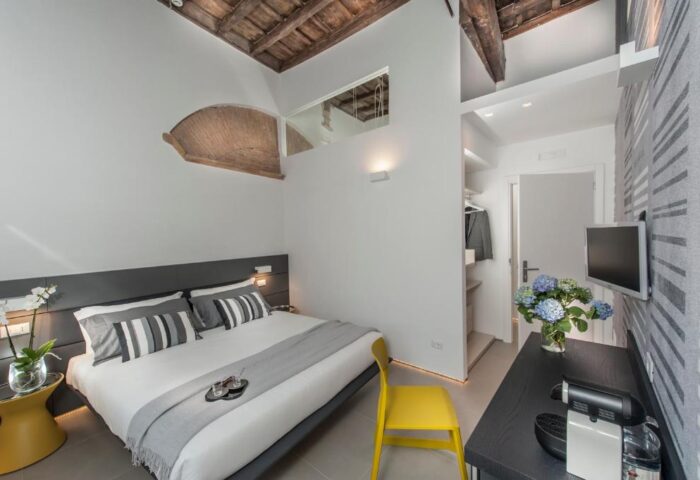 B&B First Floor room: Gay-friendly hotel bedroom with a bed, closet, TV, flowers, and coffee machine. Modern design, comfortable for gay travelers.