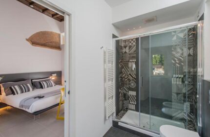 B&B First Floor: Gay-friendly hotel room with a shower and view of the bedroom. The shower has patterned tiles and glass doors. Modern design.