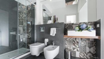 B&B First Floor bathroom in a gay-friendly hotel. Shower, toilet, and sink with patterned tiles. Modern design for gay men travelers.