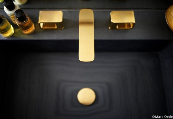 BEYOND by Geisel gay-friendly hotel: Close-up of a sleek, dark sink with gold fixtures. Upscale design at this gay travel destination.