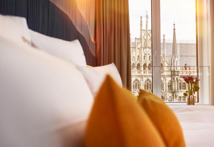 BEYOND by Geisel, a gay-friendly hotel: Room view with pillows and Munich's city hall. A top choice for gay men's travel in Germany.