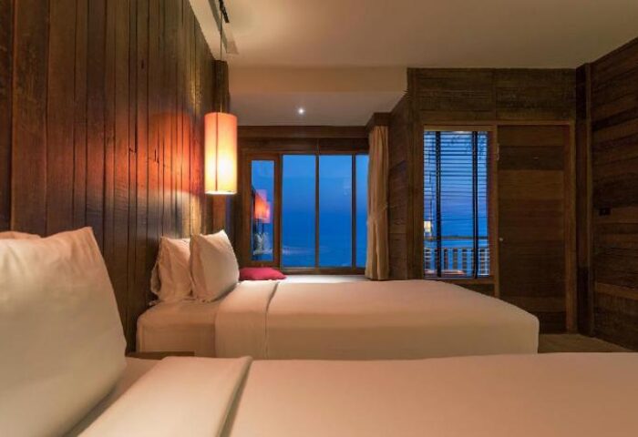 Baan Ploy Sea gay-friendly hotel room. Two beds with white linens, wood walls, and ocean view. A cozy, inviting space for gay travelers.