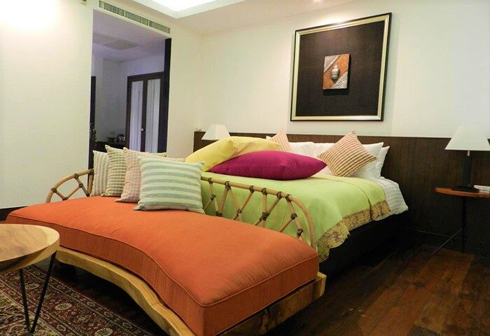 Baan Saen Fang Chiang Mai gay-friendly hotel room. Colorful pillows on bed and chaise lounge. Interior design at gay travel hotel.