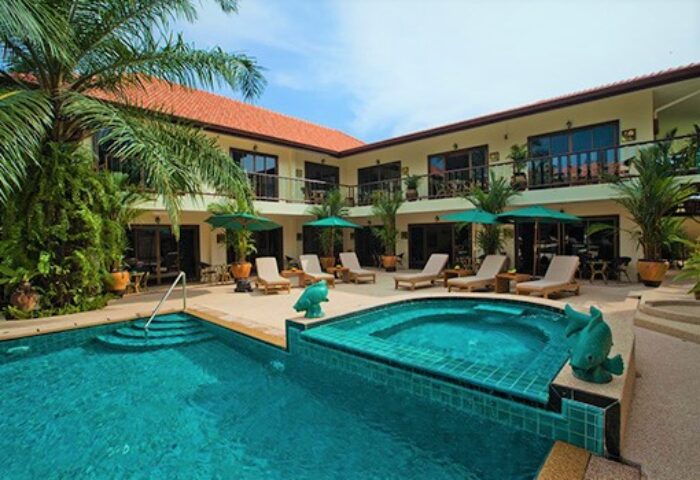 Baan Souy Resort pool area. Gay-friendly hotel with sun loungers, umbrellas, and tropical plants. Ideal for gay men's travel.