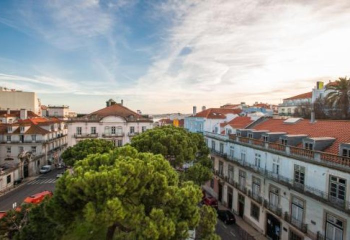 Gay-friendly Bairro Alto Hotel view. Lisbon cityscape featuring historic buildings, red tile roofs, and green trees. A top choice for gay travel.