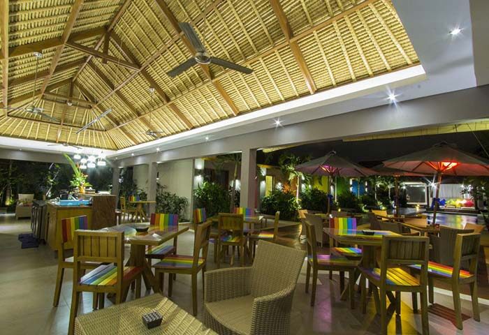 Balinea Villa & Spa gay-friendly hotel restaurant. Thatched roof, ceiling fans, rainbow chairs, tables, and umbrellas. Outdoor dining area.