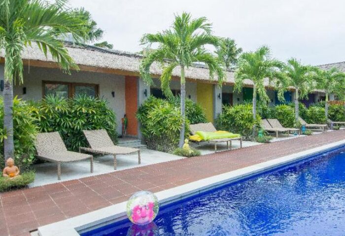 Balinea Villa & Spa pool view. Gay-friendly hotel with colorful rooms, palm trees, and lounge chairs. Perfect for gay travel and relaxation.