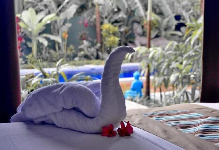 Balinea Villa & Spa gay-friendly hotel room detail. Towel swan on bed with flowers. Pool and garden view. Gay travel luxury.