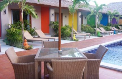 Balinea Villa & Spa, a gay-friendly hotel. Poolside seating with rainbow-colored bungalows in the background. A tropical gay travel destination.