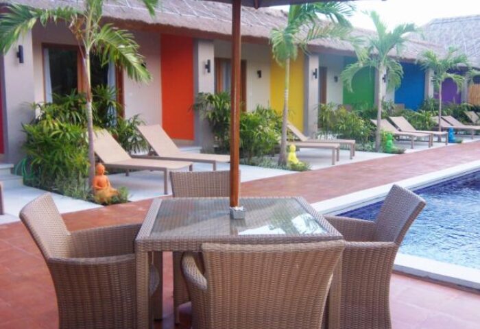 Balinea Villa & Spa, a gay-friendly hotel. Poolside seating with rainbow-colored bungalows in the background. A tropical gay travel destination.