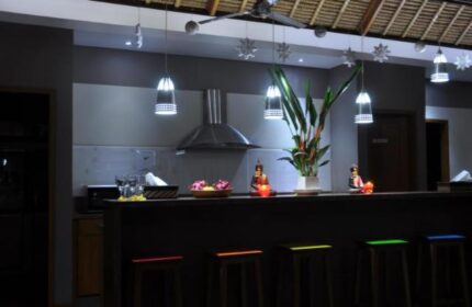 Balinea Villa & Spa kitchen. Gay-friendly hotel bar with stools, plants, and Buddha statues. Modern design, perfect for gay men's travel.