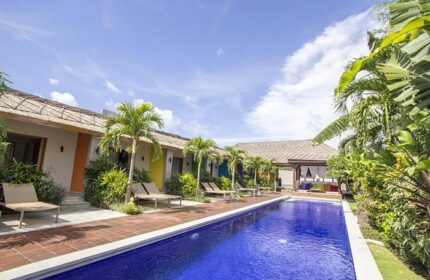 Balinea Villa & Spa pool view. Gay-friendly hotel with colorful bungalows, palm trees, and lounge chairs. Ideal for gay travel and relaxation.