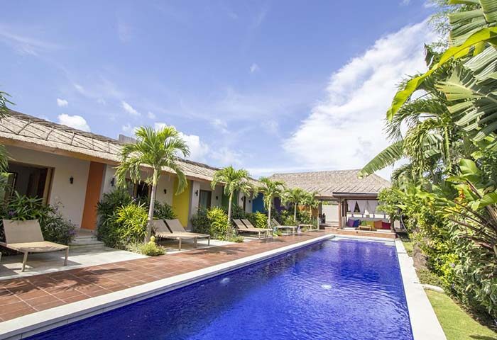 Balinea Villa & Spa pool view. Gay-friendly hotel with colorful bungalows, palm trees, and lounge chairs. Ideal for gay travel and relaxation.
