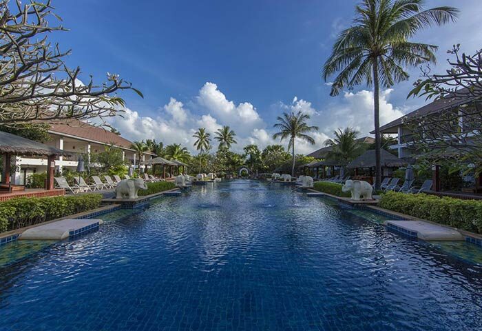 Bandara Resort & Spa pool view. Gay-friendly hotel with palm trees, elephant statues, and blue sky. A great place for gay travel and relaxation.