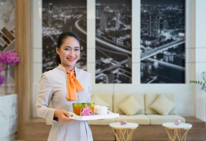 Bandara Suites Silom, a gay-friendly hotel. Staff member holding a tray with drinks. Welcoming service in Bangkok, Thailand.