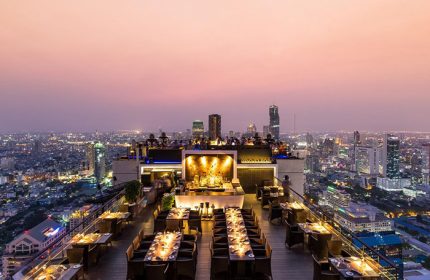 Rooftop bar at gay-friendly Banyan Tree Bangkok hotel. City skyline view. Moon Bar offers cocktails, dining, and a vibrant atmosphere.