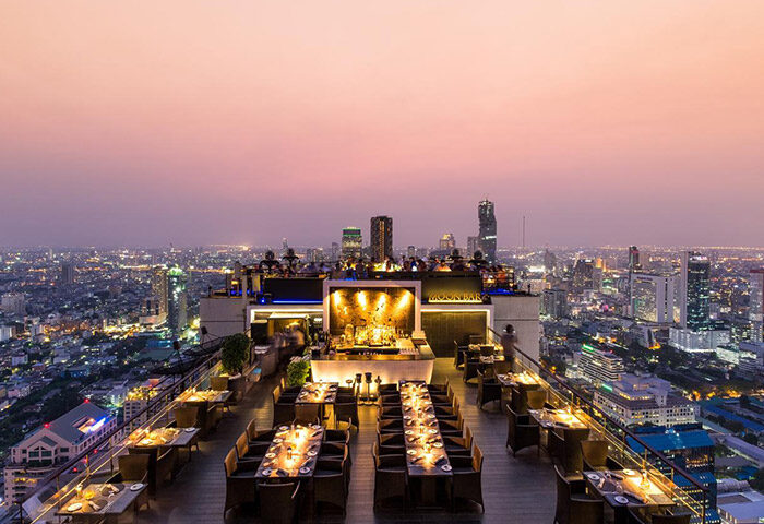 Rooftop bar at gay-friendly Banyan Tree Bangkok hotel. City skyline view. Moon Bar offers cocktails, dining, and a vibrant atmosphere.