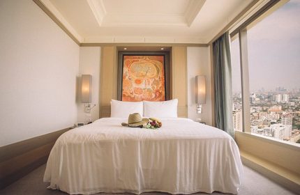 Banyan Tree Bangkok gay-friendly hotel room. King bed, city view, hat, and fruit. Luxury travel for gay men in Thailand.