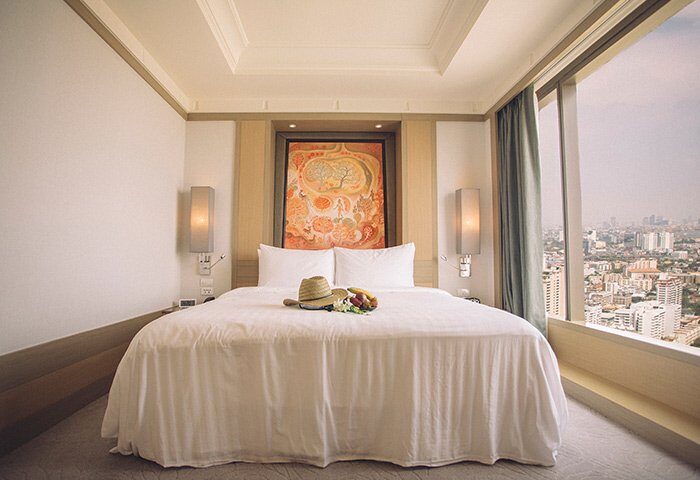 Banyan Tree Bangkok gay-friendly hotel room. King bed, city view, hat, and fruit. Luxury travel for gay men in Thailand.